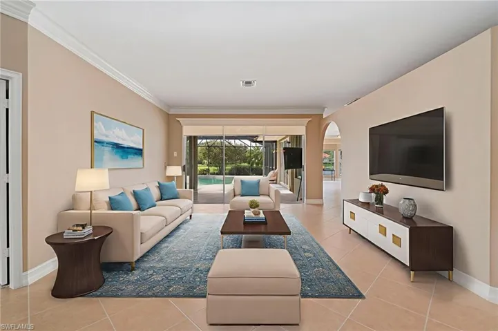 Living area featuring light tile patterned floors, arched walkways, and ornamental molding