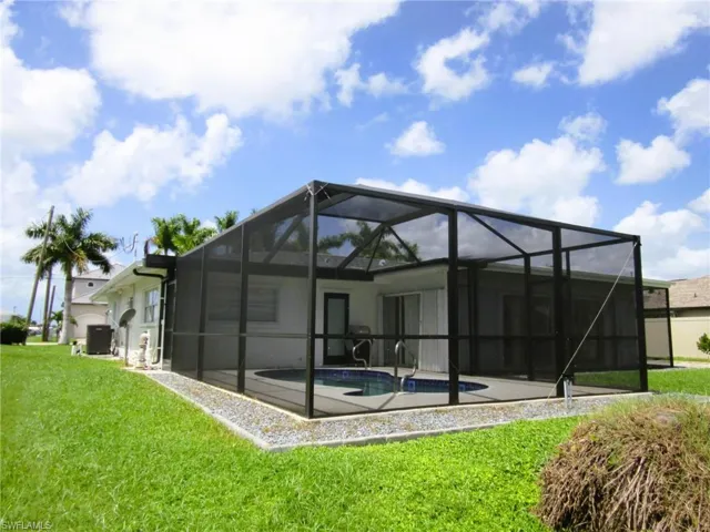 Back of property with glass enclosure, a yard, and a patio area