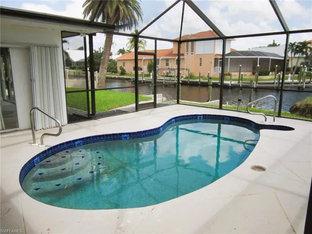 View of pool featuring glass enclosure and a water view