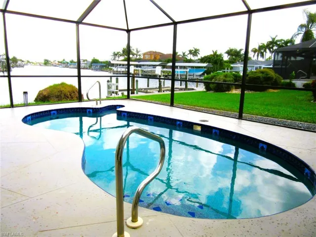 View of swimming pool featuring a water view, a lawn, and a lanai