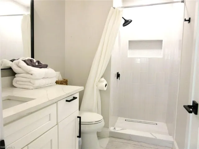 Bathroom featuring vanity, toilet, and curtained shower