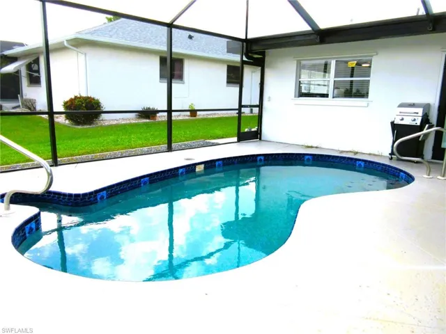 View of swimming pool featuring glass enclosure, a yard, and a patio area