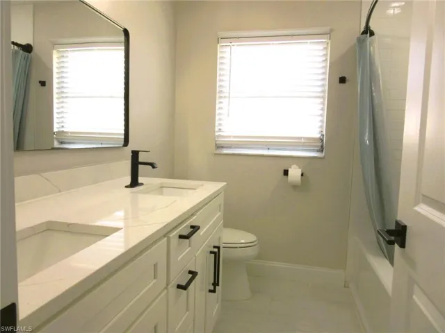 Full bathroom featuring vanity, toilet, tile patterned floors, and shower / bathtub combination with curtain