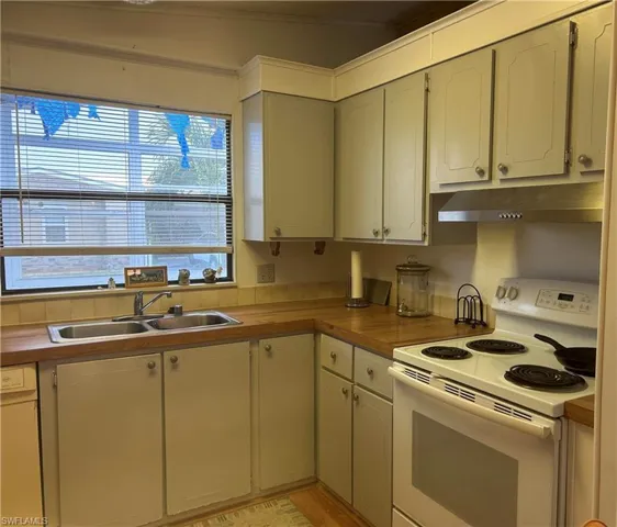 Kitchen with sink, light hardwood / wood-style flooring, and white appliances