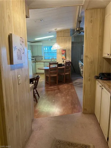 Dining space with ceiling fan, carpet flooring, and wood walls