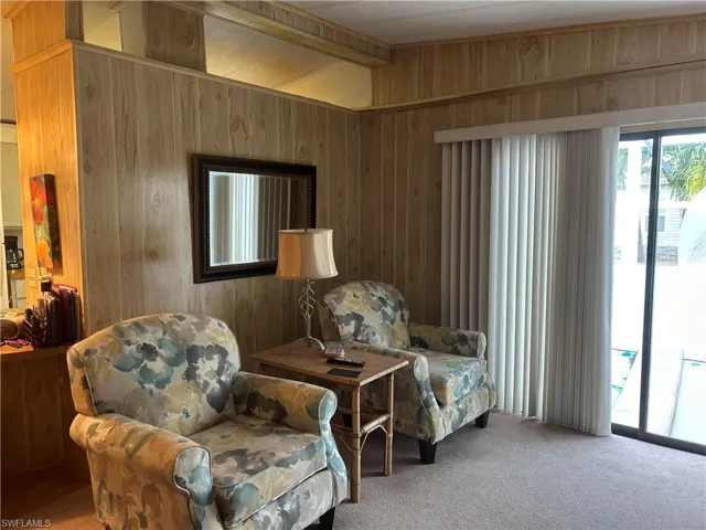Sitting room with wood walls, vaulted ceiling, and carpet flooring