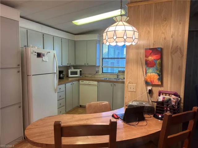 Kitchen featuring sink, white appliances, green cabinets, and light hardwood / wood-style flooring