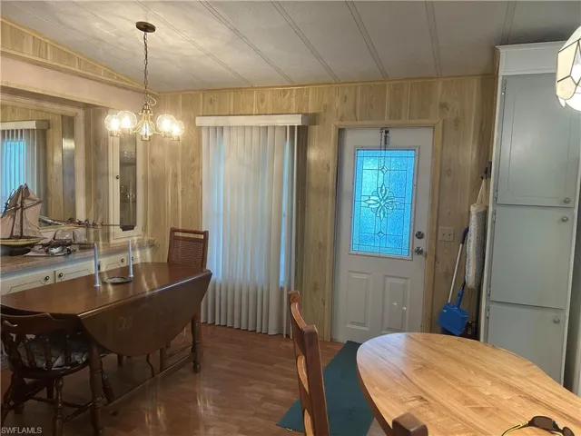 Dining space featuring wood walls, dark wood-type flooring, and an inviting chandelier