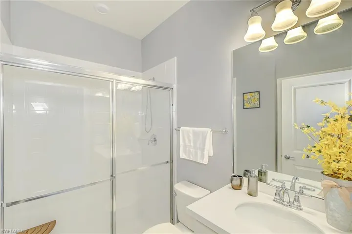 Bathroom featuring an enclosed shower, vanity, and toilet