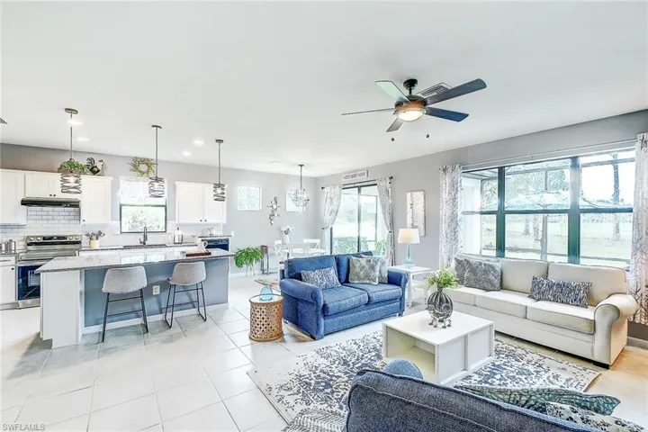 Tiled living room featuring ceiling fan, sink, and a healthy amount of sunlight