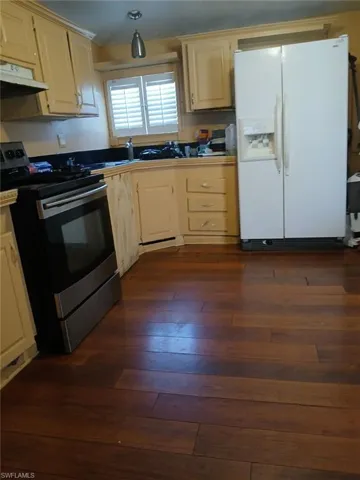 Kitchen with electric range, dark hardwood / wood-style flooring, and white refrigerator with ice dispenser