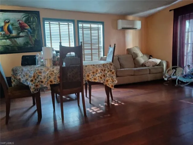 Dining area with hardwood / wood-style floors and an AC wall unit