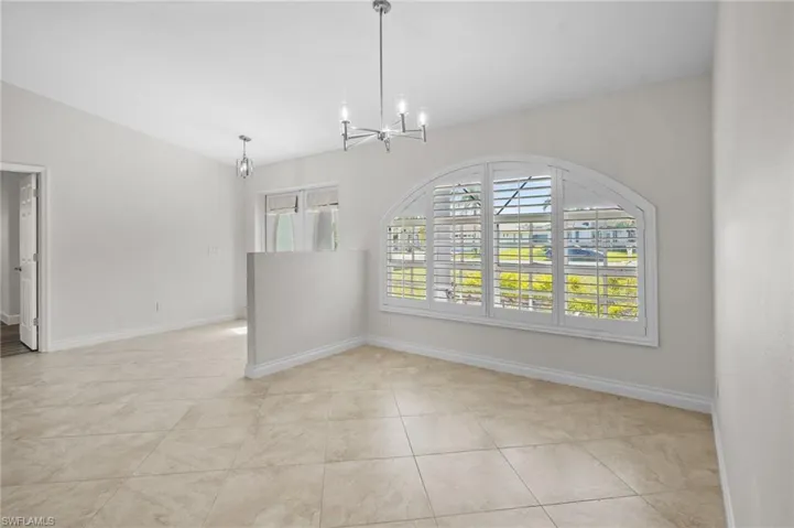Unfurnished dining area with a chandelier, vaulted ceiling, and light tile patterned floors