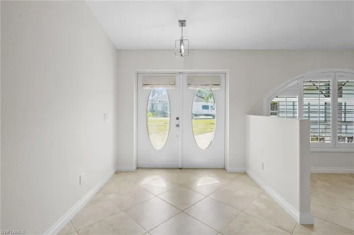 Tiled entryway featuring french doors and baseboards