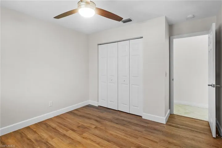 Unfurnished bedroom featuring wood finished floors, a closet, and a ceiling fan