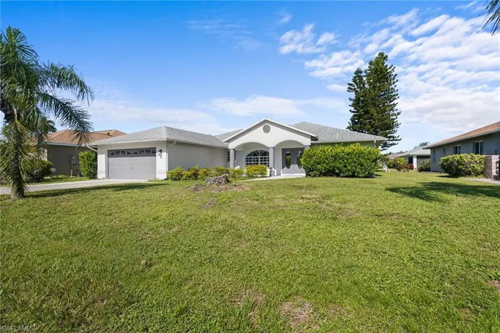 Single story home with a garage, driveway, a front yard, and stucco siding