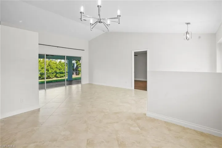 Tiled spare room with a chandelier and high vaulted ceiling