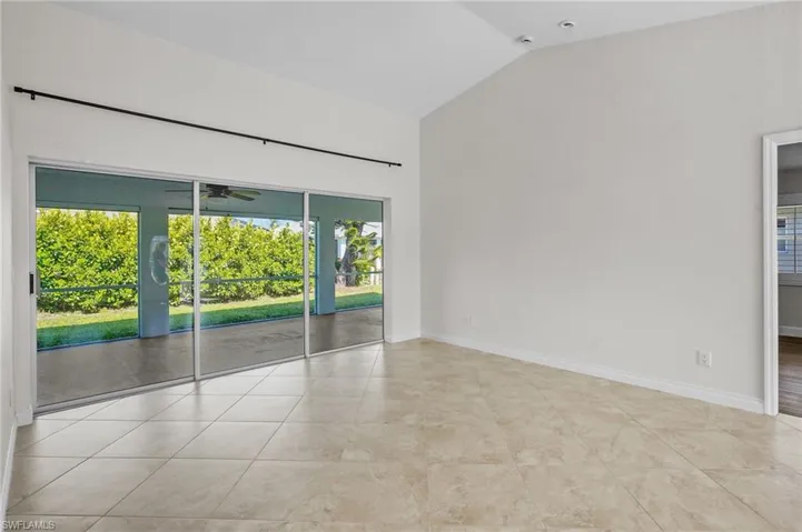 Empty room with lofted ceiling, tile patterned floors, and a ceiling fan