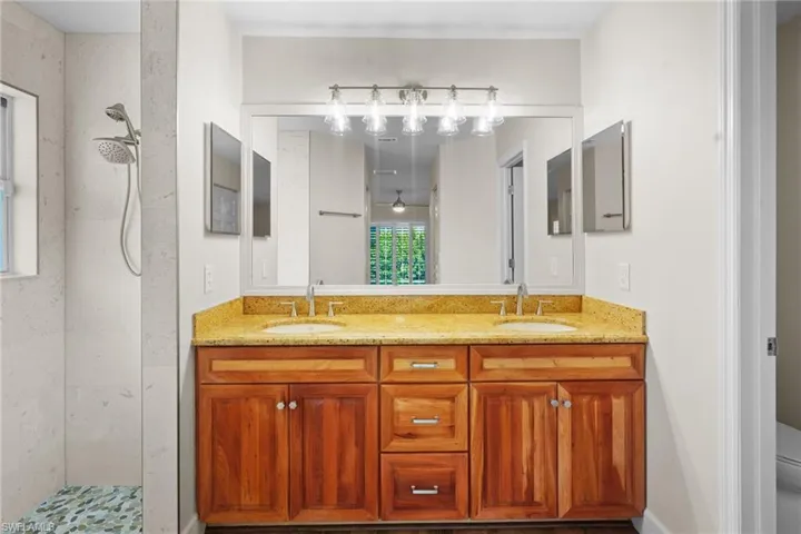 Full bath with double vanity and tiled shower