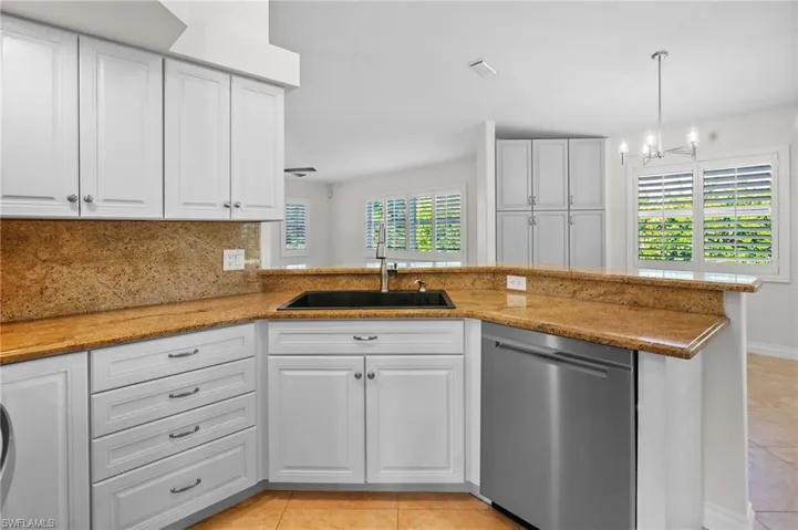 Kitchen with dishwasher, light tile patterned floors, white cabinets, and light stone countertops