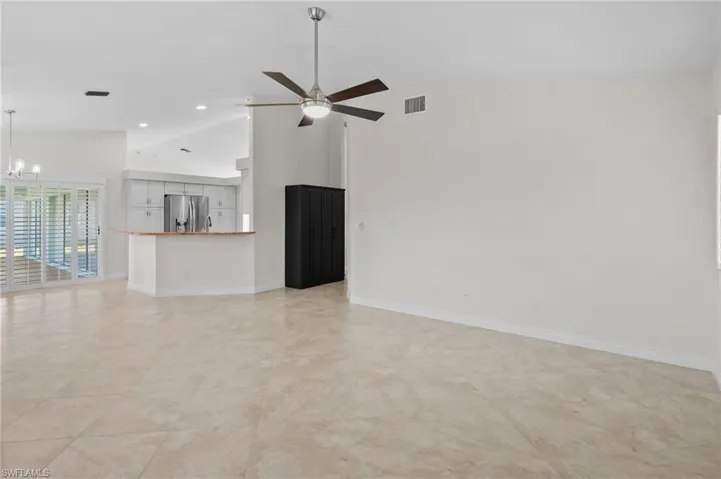 Unfurnished living room with high vaulted ceiling, ceiling fan, recessed lighting, and a chandelier