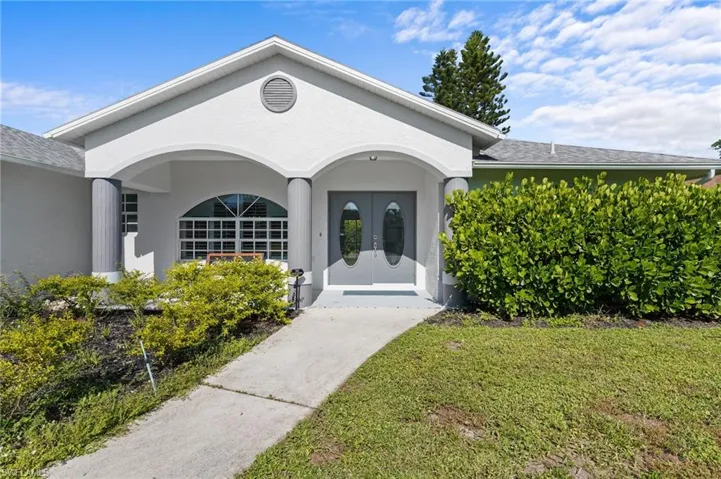 Entrance to property with french doors, roof with shingles, a lawn, and stucco siding