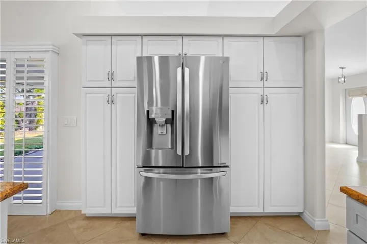 Kitchen featuring stainless steel fridge with ice dispenser and white cabinetry