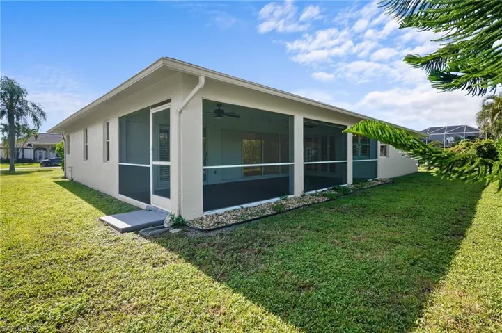 View of property exterior featuring a sunroom, a yard, stucco siding, and a ceiling fan
