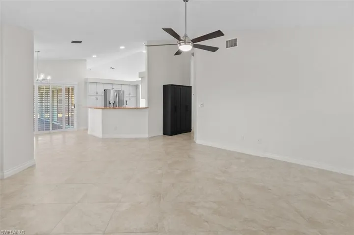 Unfurnished living room featuring high vaulted ceiling, a chandelier, ceiling fan, and recessed lighting