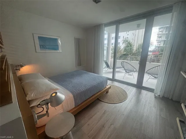 Bedroom with hardwood / wood-style flooring, a wall of windows, and access to outside