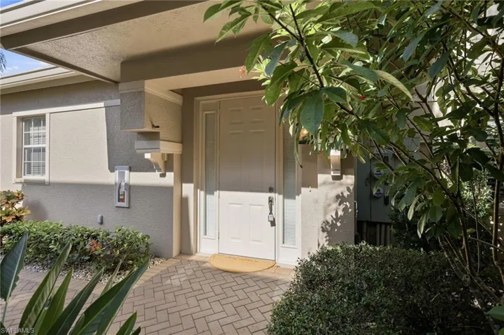 A charming private entrance surrounded by mature tropical landscaping creates a warm and inviting first impression. This luxury coach home offers the convenience of private elevator access, brick paver walkway, and a beautifully maintained setting within the gated community of Regency Reserve at The Vineyards, where elegant architecture meets the relaxed Naples lifestyle.