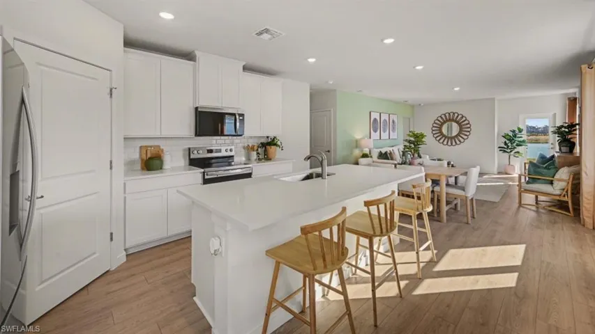 Open-concept living area featuring a kitchen with a large island, white cabinetry, and stainless steel appliances