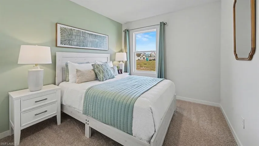 Bedroom featuring neutral carpeting, a window with exterior views, and a wall with a subtle green accent color
