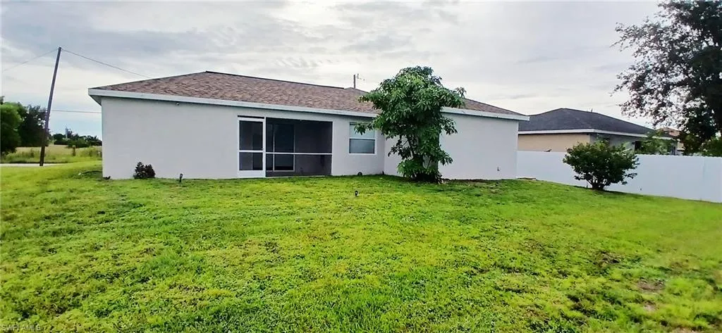 Back of house with stucco siding and roof with shingles