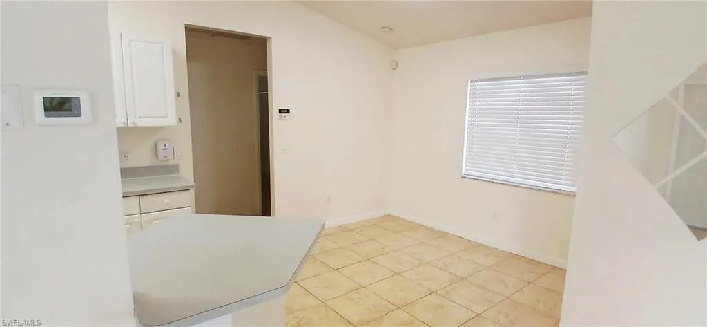 Unfurnished dining area with light tile patterned flooring and baseboards