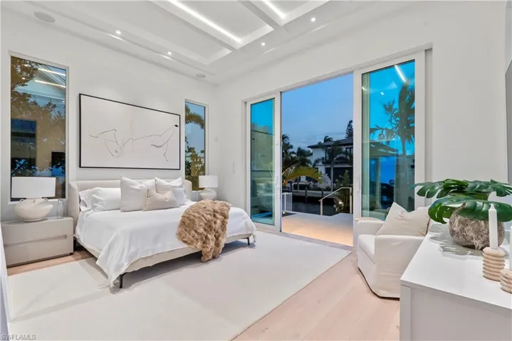 Bedroom featuring beam ceiling, access to outside, light hardwood / wood-style flooring, and coffered ceiling