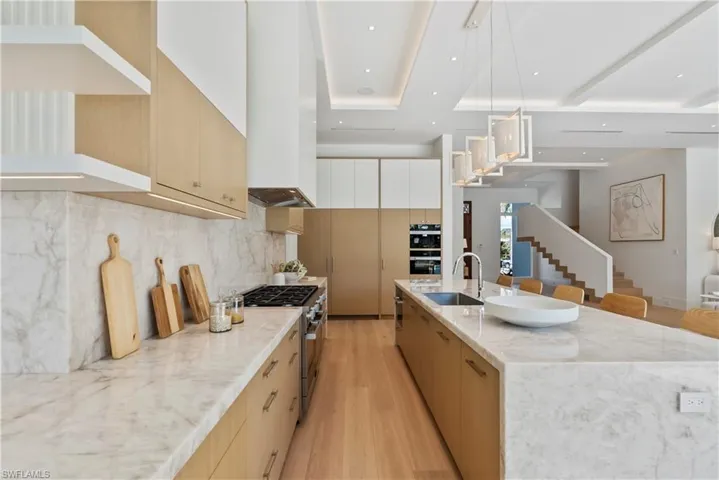 Kitchen with light wood-type flooring, stainless steel range, a spacious island, sink, and pendant lighting