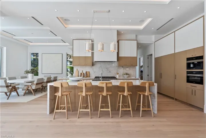 Kitchen featuring a kitchen breakfast bar, a kitchen island with sink, light hardwood / wood-style flooring, and white cabinets