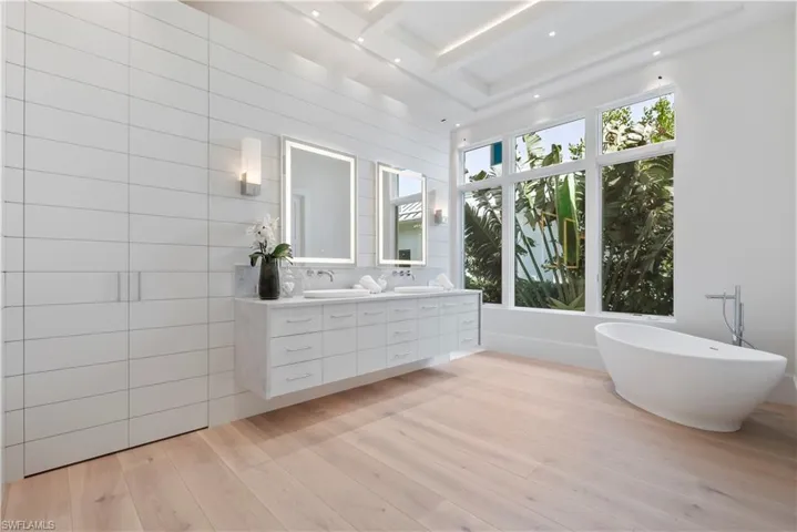 Bathroom featuring beamed ceiling, a bath, backsplash, wood-type flooring, and vanity