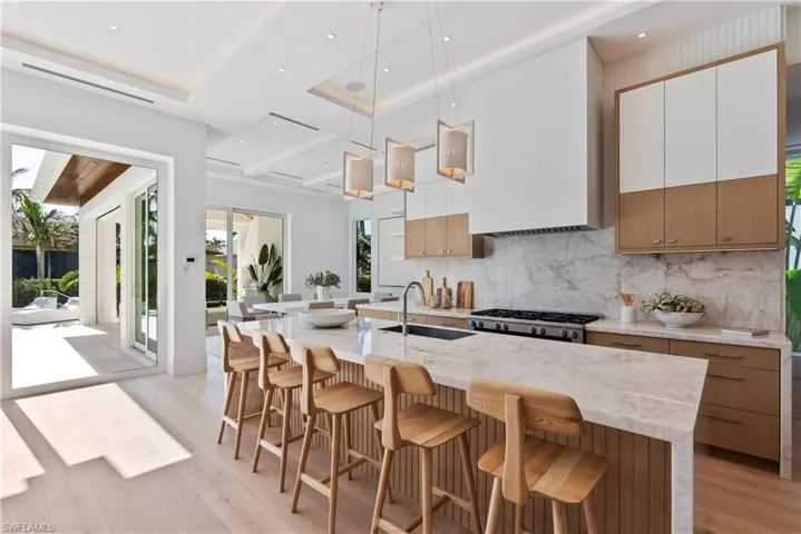 Kitchen featuring a large island, decorative light fixtures, stainless steel range oven, and white cabinetry