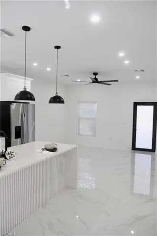 Kitchen with marble finish floor, visible vents, stainless steel refrigerator with ice dispenser, and white cabinets
