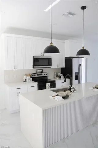 Kitchen featuring visible vents, marble finish floor, stainless steel appliances, light countertops, and a sink