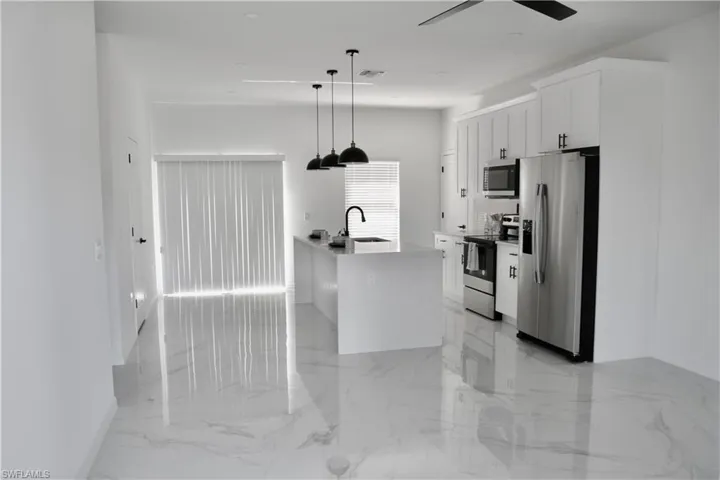 Kitchen featuring stainless steel appliances, a sink, visible vents, white cabinets, and marble finish floor