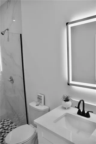Full bathroom with toilet, a marble finish shower, and vanity