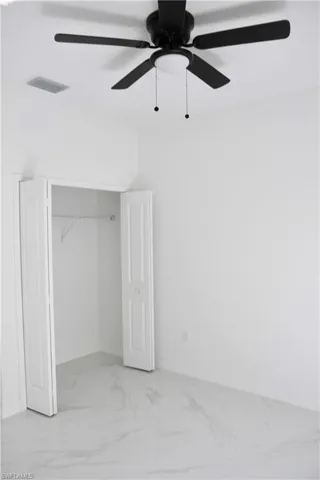 Unfurnished bedroom with baseboards, visible vents, a ceiling fan, marble finish floor, and a closet