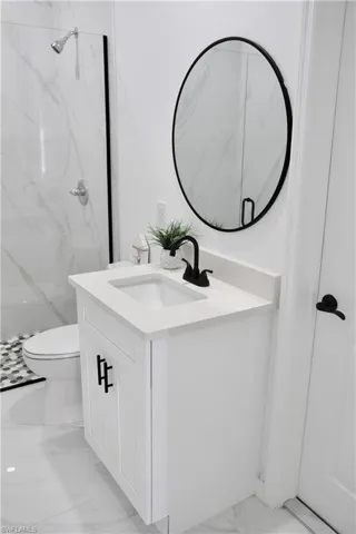 Full bath with toilet, marble finish floor, a marble finish shower, and vanity