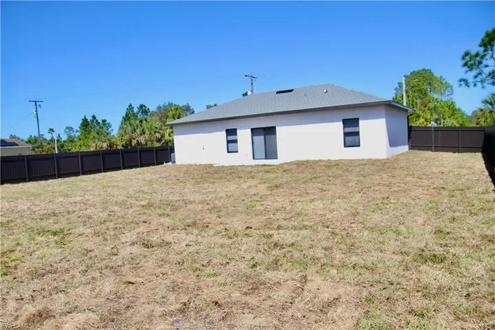 Rear view of house featuring stucco siding, a fenced backyard, and a yard