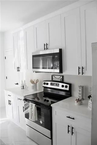 Kitchen featuring white cabinets, marble finish floor, stainless steel appliances, and light countertops