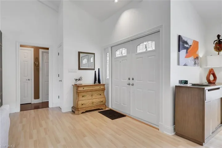 Entrance foyer with light wood-style flooring and a high ceiling