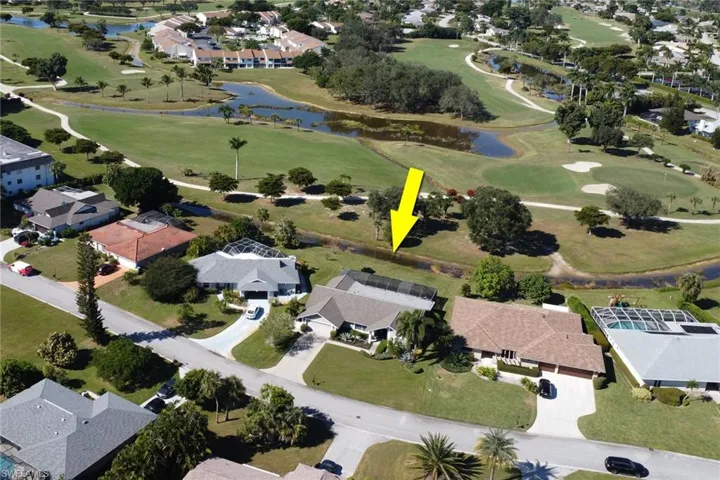 Aerial view of property and surrounding area with nearby suburban area, a local golf course, and a large body of water